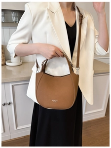 Detail of brown lychee leather crescent bag with silver hardware and adjustable strap