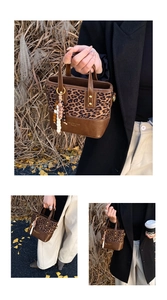 Detail of leopard print bucket bag with wooden bead charm against autumn leaves background