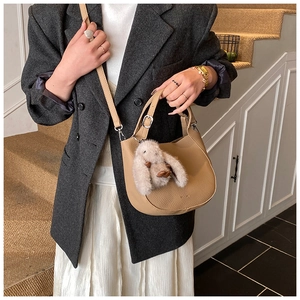 Detail of camel crescent bucket bag with lychee grain leather and plush bunny charm
