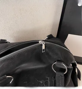 Close-up of smooth silver metal zipper and embossed texture on black tote bag