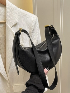 Vintage black pebble leather crescent crossbody bag with gold hardware held by model