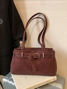 Sac fourre-tout bordeaux avec boucle argentée sur un fond de bureau professionnel