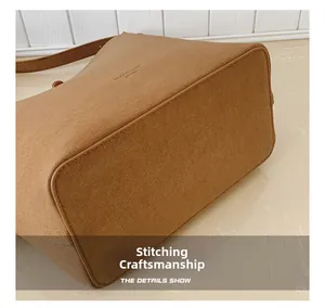 Détail du sac seau marron montrant les coutures soignées et le logo en relief