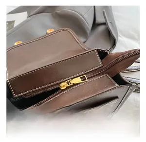Détail macro de la fermeture éclair dorée et des coutures sur un sac à dos en cuir marron