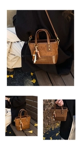 Detail of a brown bucket bag with smooth leather finish and ethnic wood bead pendant