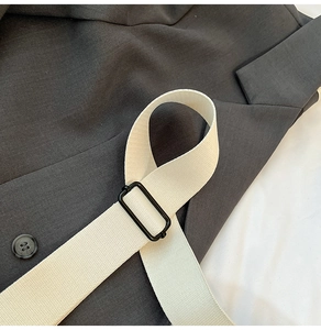 Détail de la texture grise avec ceinture tressée crème et boucle métallique noire