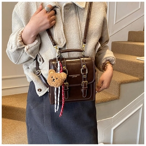 Détail du sac à dos vintage en cuir synthétique marron foncé avec pendentif ours peluche