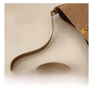 Détail du sac seau en cuir marron texturé avec boucle en métal doré et bandoulière
