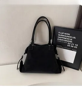 Detailed shot of a matte black tote bag with slender straps and metal ring accents