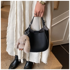 Detail of black lychee grain leather bucket bag with a cute plush rabbit charm