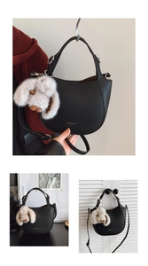 Detail of black pebbled leather hobo bag with adjustable strap and plush rabbit charm