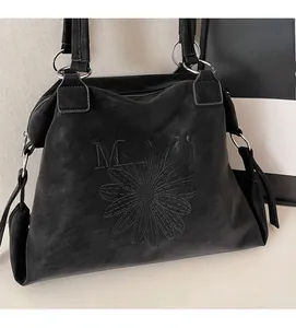 Close-up of vintage black tote bag featuring embossed floral patterns and Malodi metal rings