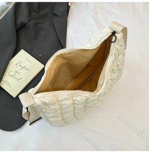 Détail d'un sac nuage matelassé beige avec texture plissée douce et large bandoulière
