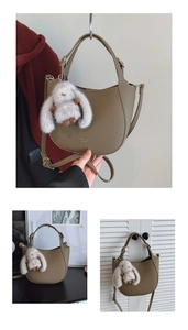 Detail of khaki hobo bag featuring litchi grain texture and a plush rabbit charm