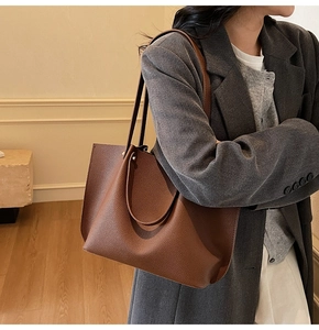 Close-up of brown pebbled leather tote bag worn with a gray blazer for office wear