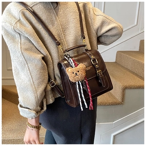 Détail d'un sac à dos vintage en cuir ciré marron avec pendentif ours et ferrures dorées