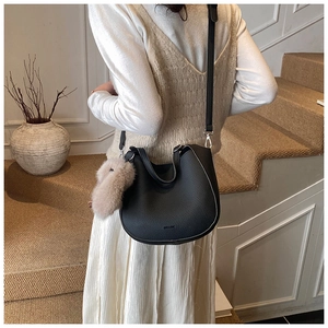 Detail of black lychee grain saddle bag with plush rabbit charm and silver metal buckle