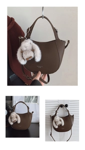 Detail of dark brown crescent bag with pebble leather texture and plush bunny charm