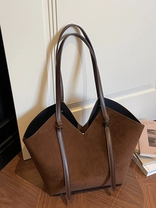 Vintage dark brown frosted tote bag with V-shaped opening on a stylish wooden floor
