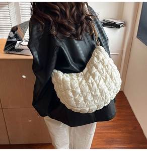 Gros plan du sac croissant matelassé beige à l'épaule, montrant la texture douce et rembourrée