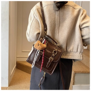 Détail d'un sac à dos vintage en cuir ciré avec lettrage doré et pendentif ourson