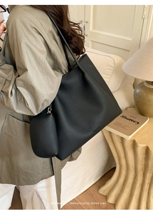 Détail d'un grand cabas en cuir grainé noir avec pochette porté par un mannequin
