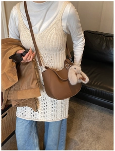 Brown faux leather crescent bag with adjustable strap and grey plush rabbit pendant detail
