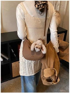 Detailed shot of brown lychee grain leather crescent bag with a cute plush rabbit charm