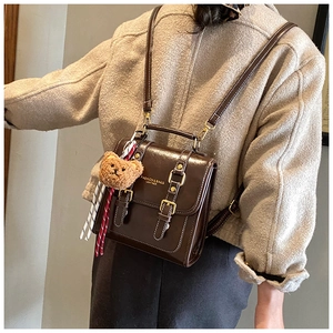 Détail du sac à dos vintage en similicuir marron avec coutures et breloque ours