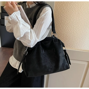 Side view of black tote bag with embroidered daisy and silver ring connectors on model