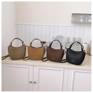 Detail of four half-moon faux leather bags in olive, camel, brown and black colors