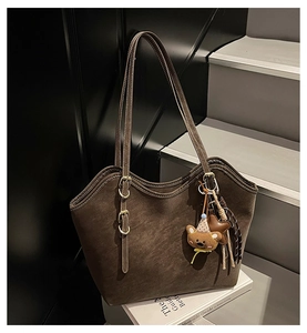 Detail of a brown tote bag with star and bear charms on a minimalist stair background