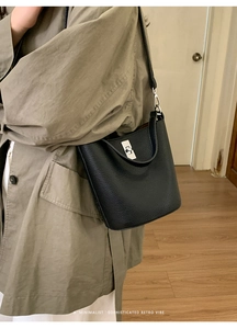 Détail du sac seau noir en cuir grainé avec fermoir rotatif argenté et style minimaliste