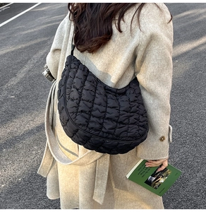 Détail du sac nuage noir matelassé porté sur un manteau en cachemire beige élégant
