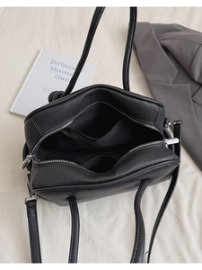 Detailansicht der schwarzen Tasche mit Lychee-Leder, Doppelreißverschluss und Innenraum