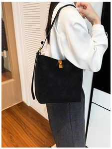 Détail du sac seau noir avec un fermoir rotatif rectangulaire en métal doré poli