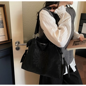 Détail du sac cabas en daim noir avec broderie Malaoli et écusson floral de marguerite