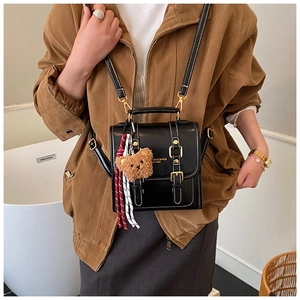Détail du sac à dos vintage en cuir ciré noir avec coutures contrastées et pendentif ours