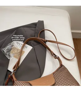 Detail of a brown houndstooth shoulder bag featuring an adjustable leather strap and silver buckle