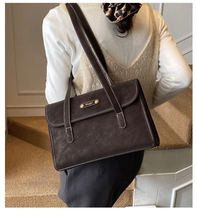 Close-up of vintage dark brown tote bag with white contrast stitching and gold metal logo