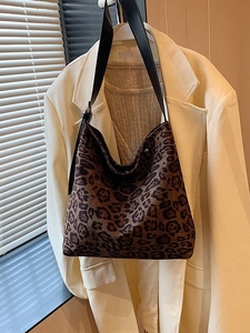 Borsa hobo alla moda con stampa leopardata e tracolla in pelle su un blazer bianco