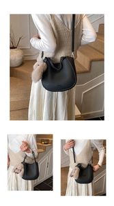 Detail of black pebbled leather hobo bag with a cute plush rabbit charm on strap