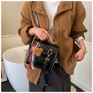 Détail du sac à dos vintage en cuir ciré noir avec coutures blanches et breloque ours