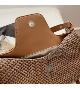 Close-up of magnetic buckle closure on woven shoulder bag with brown leather details