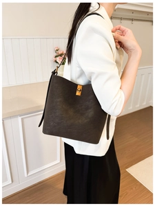Détail du sac seau en cuir marron foncé avec fermoir doré porté en situation réelle