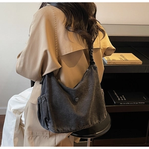 Detailed view of grey washed denim hobo bag featuring side pleated pockets and metal logo