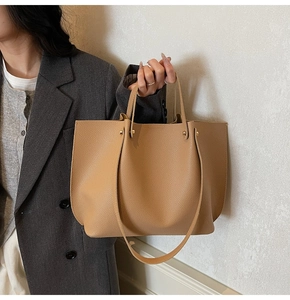 Close-up of tan pebbled leather tote bag with gold rivets and dual strap design for commute