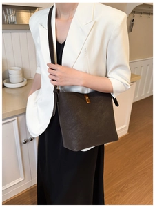 Détail du sac seau en cuir mat marron foncé avec un fermoir tournant en métal doré chic