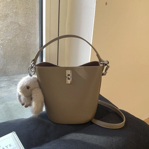 Détail d'un sac seau en cuir grainé kaki avec fermoir argenté et breloque lapin en peluche