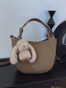 Chic khaki pebbled leather handbag with plush rabbit charm and crossbody strap